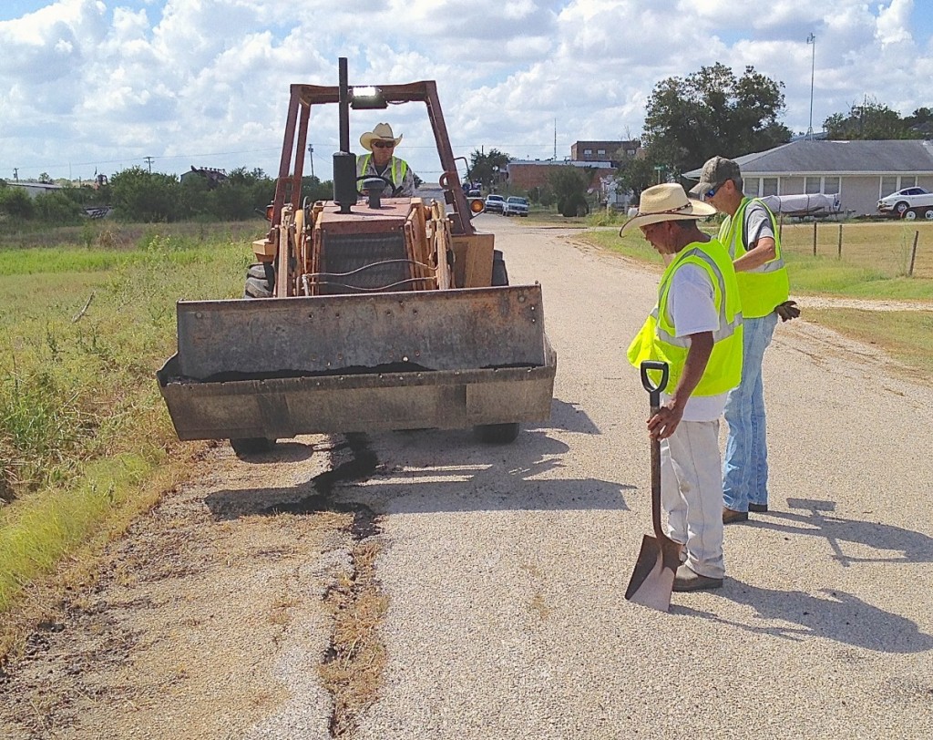 James Naivar uses a front-end loader to prepare the road so his workers can fill in some big cracks.